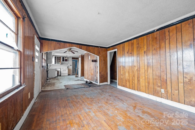 unfurnished living room with hardwood / wood-style floors, wooden walls, and ornamental molding