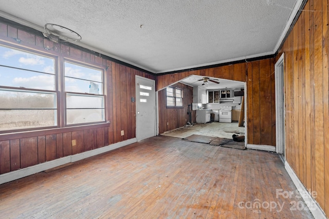 unfurnished living room with a healthy amount of sunlight, crown molding, a textured ceiling, and wood-type flooring