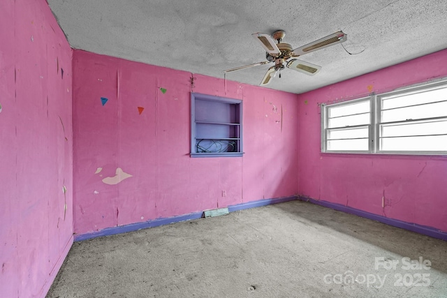 spare room featuring ceiling fan, a textured ceiling, and built in shelves