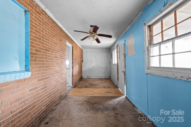 interior space with brick wall, ornamental molding, and a textured ceiling