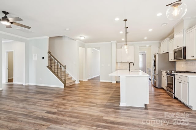 kitchen featuring white cabinetry, appliances with stainless steel finishes, light countertops, and decorative light fixtures