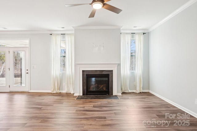 unfurnished living room featuring a fireplace with flush hearth, crown molding, baseboards, and wood finished floors