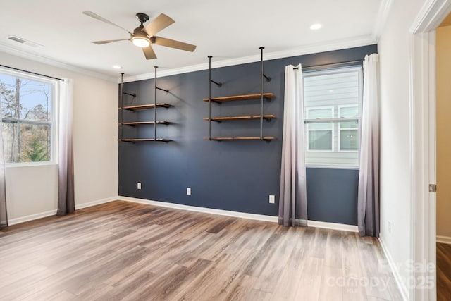 empty room with wood finished floors, visible vents, and crown molding