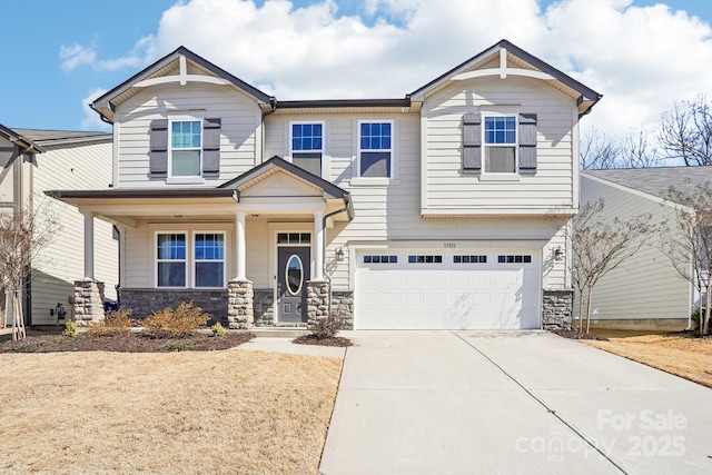 craftsman house with covered porch, stone siding, an attached garage, and driveway