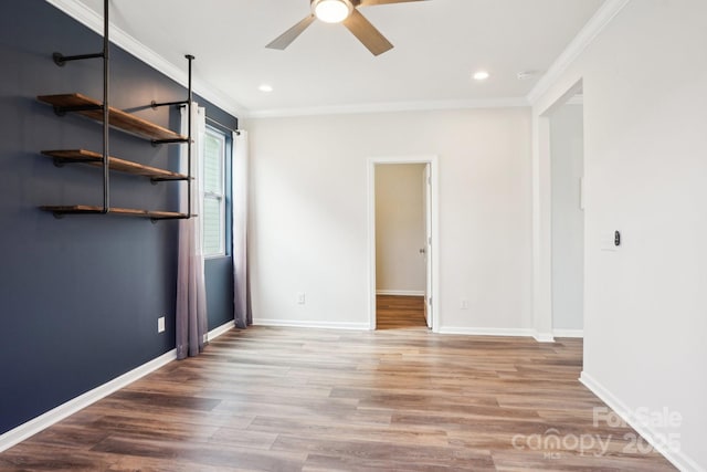 spare room with ornamental molding, wood finished floors, and a ceiling fan