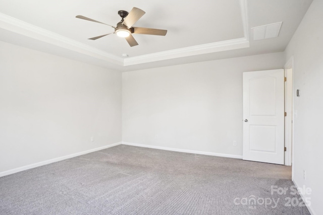 empty room with baseboards, a raised ceiling, a ceiling fan, light colored carpet, and ornamental molding