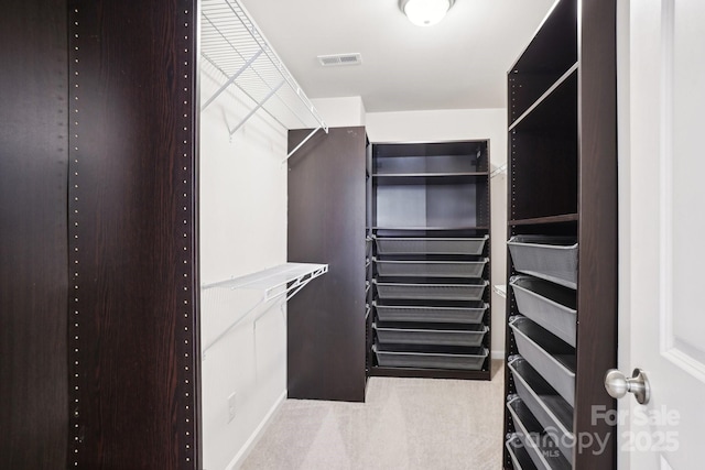 spacious closet featuring light colored carpet and visible vents