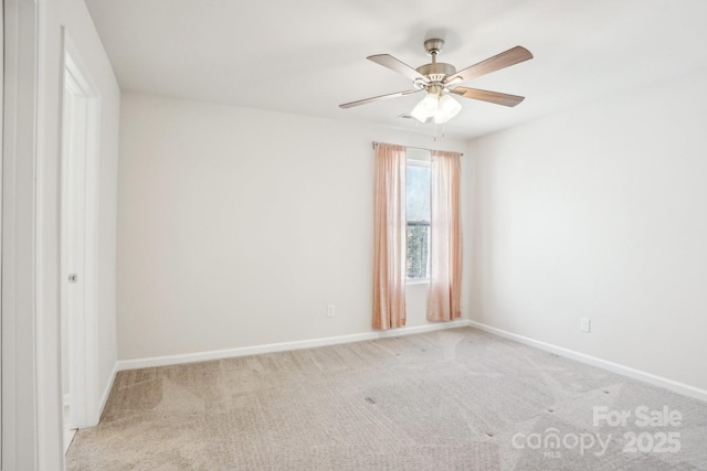 spare room with a ceiling fan, light carpet, and baseboards