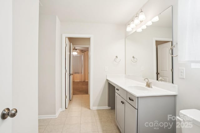 bathroom with tile patterned flooring, baseboards, vanity, and toilet