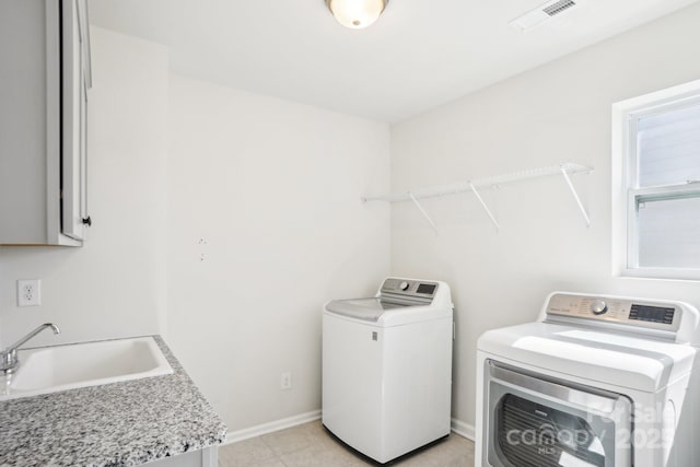 washroom featuring independent washer and dryer, visible vents, a sink, and baseboards