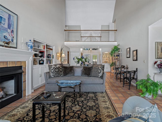 tiled living room with a tiled fireplace, built in features, and a high ceiling