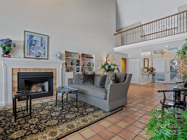 tiled living room with a notable chandelier, a tile fireplace, and a high ceiling