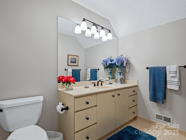 bathroom with tile patterned floors, toilet, vaulted ceiling, a textured ceiling, and vanity