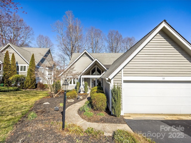 view of front of home with a shingled roof, a garage, and a front yard