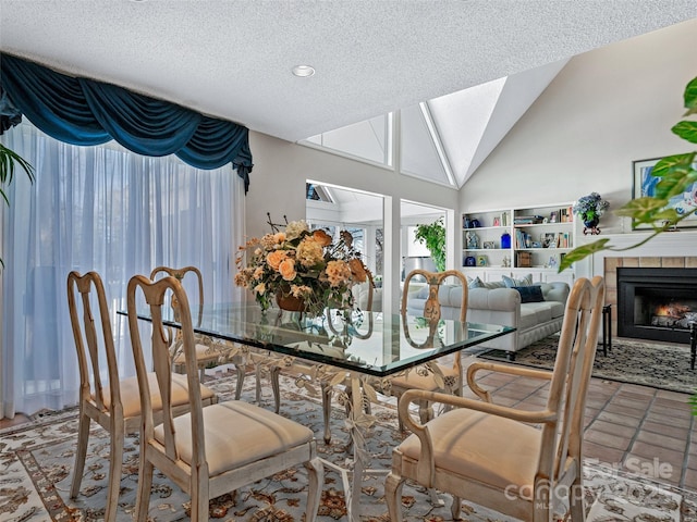 dining area featuring lofted ceiling with skylight, a tile fireplace, tile patterned floors, and a textured ceiling