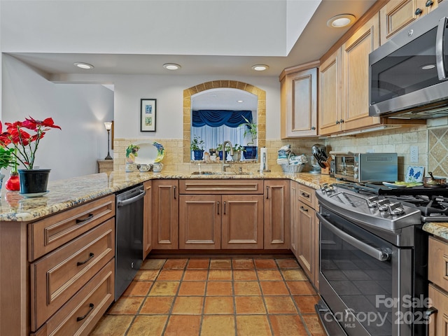 kitchen with a sink, backsplash, a toaster, and appliances with stainless steel finishes