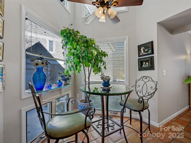 tiled dining room with a ceiling fan and baseboards