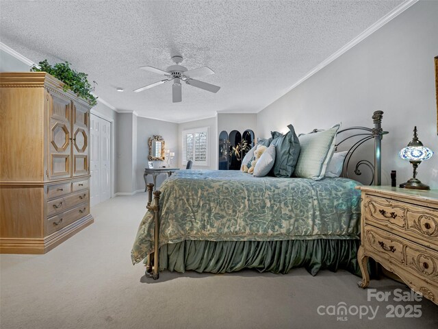bedroom featuring a closet, light carpet, a textured ceiling, ceiling fan, and ornamental molding