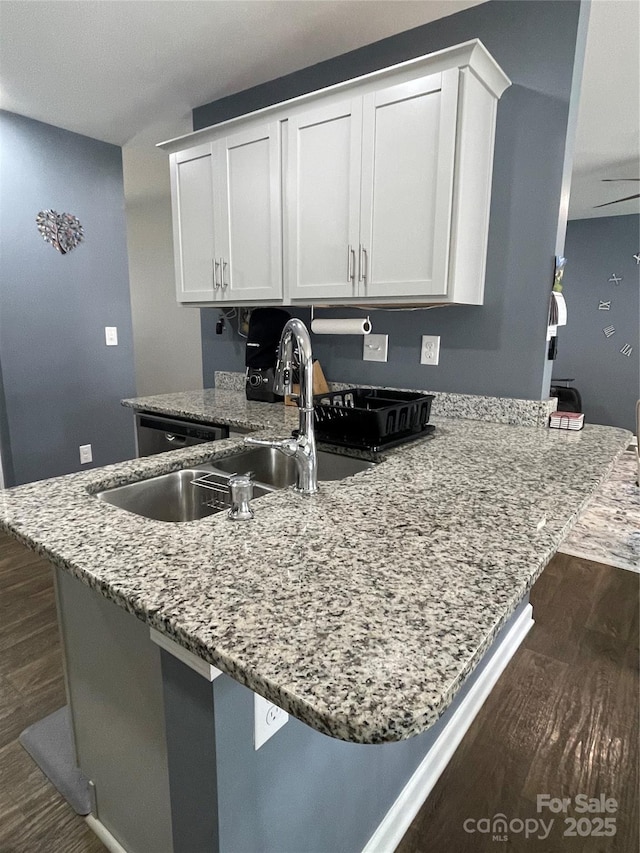 kitchen featuring dark wood-type flooring, light stone countertops, kitchen peninsula, and white cabinets