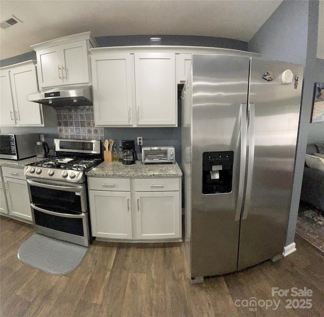 kitchen featuring appliances with stainless steel finishes, dark hardwood / wood-style floors, white cabinets, light stone countertops, and backsplash