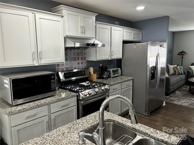 kitchen with ventilation hood, white cabinetry, appliances with stainless steel finishes, and decorative backsplash