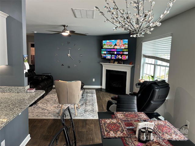 living room with dark hardwood / wood-style flooring and ceiling fan with notable chandelier