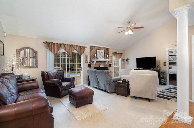 carpeted living room featuring ceiling fan, vaulted ceiling, a brick fireplace, and ornate columns