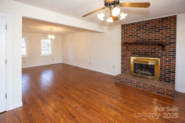 unfurnished living room with wood finished floors, baseboards, a ceiling fan, beam ceiling, and a fireplace