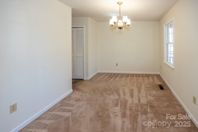 empty room with carpet flooring, an inviting chandelier, visible vents, and baseboards