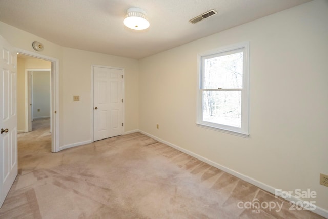 unfurnished bedroom with light carpet, visible vents, and baseboards