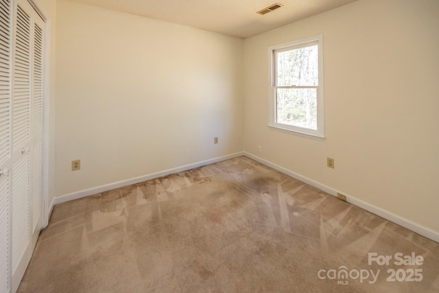 unfurnished bedroom featuring a closet, visible vents, baseboards, and carpet floors