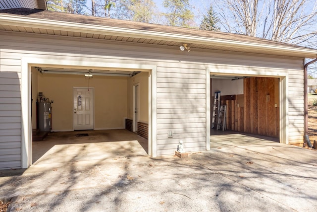 garage with visible vents, electric water heater, and driveway