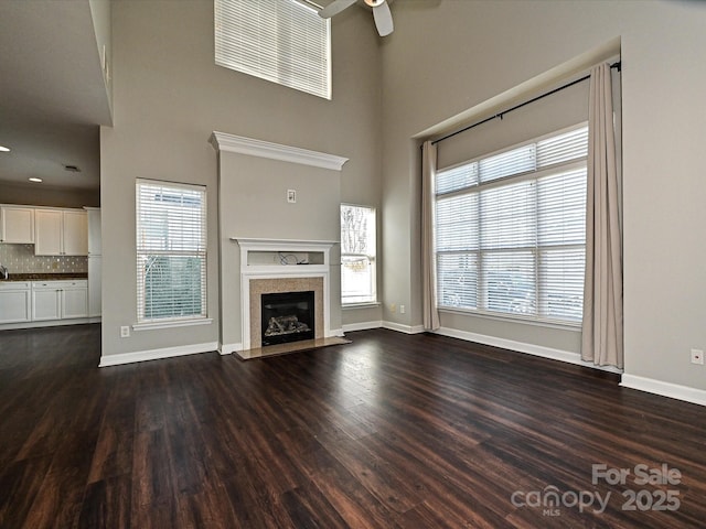 unfurnished living room with a fireplace, ceiling fan, and dark wood-type flooring