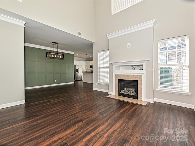 unfurnished living room featuring dark hardwood / wood-style flooring, a high end fireplace, and a healthy amount of sunlight