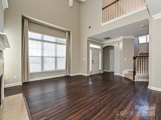 unfurnished living room with ornamental molding, dark wood-type flooring, and ceiling fan