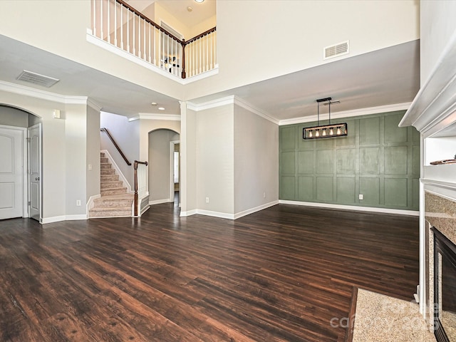 unfurnished living room featuring dark wood-type flooring, a premium fireplace, and crown molding