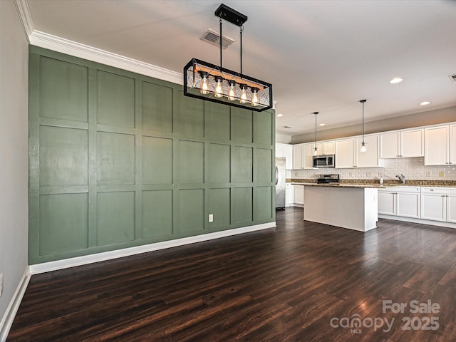 kitchen with a center island, decorative light fixtures, dark hardwood / wood-style floors, white cabinetry, and appliances with stainless steel finishes