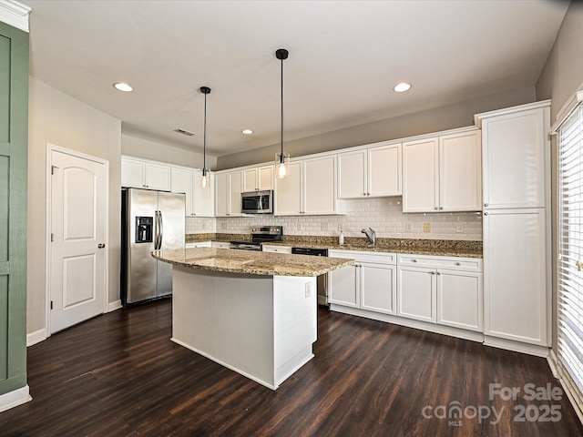 kitchen featuring pendant lighting, a center island, stone countertops, white cabinetry, and appliances with stainless steel finishes