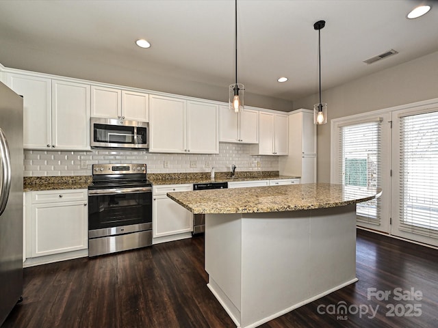 kitchen with white cabinets, stainless steel appliances, and decorative light fixtures