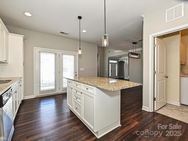 kitchen with light stone counters, dishwasher, hanging light fixtures, a center island, and white cabinetry