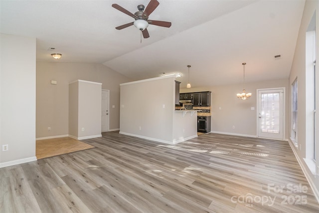 unfurnished living room with lofted ceiling, ceiling fan with notable chandelier, and wood-type flooring