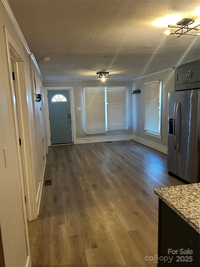 foyer featuring a healthy amount of sunlight, ornamental molding, dark hardwood / wood-style flooring, and a textured ceiling