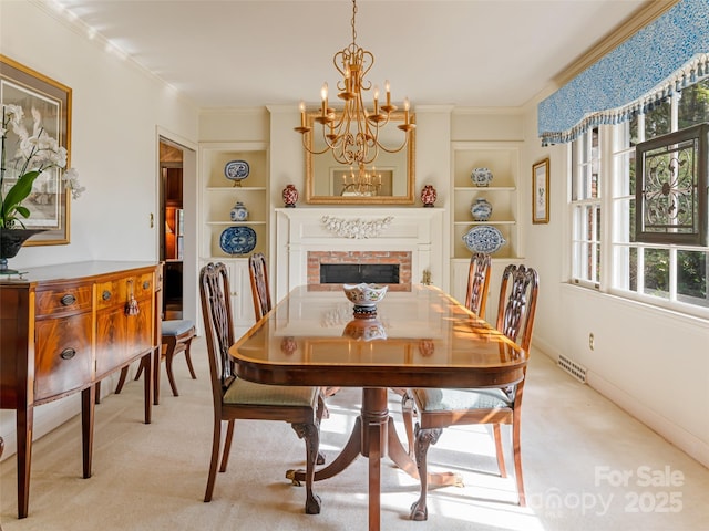 dining room with a fireplace, ornamental molding, light carpet, built in features, and a notable chandelier