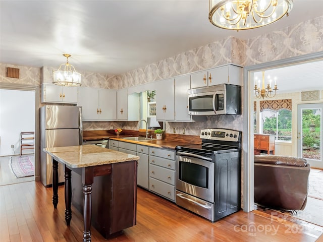 kitchen featuring hanging light fixtures, a breakfast bar, white cabinets, appliances with stainless steel finishes, and sink