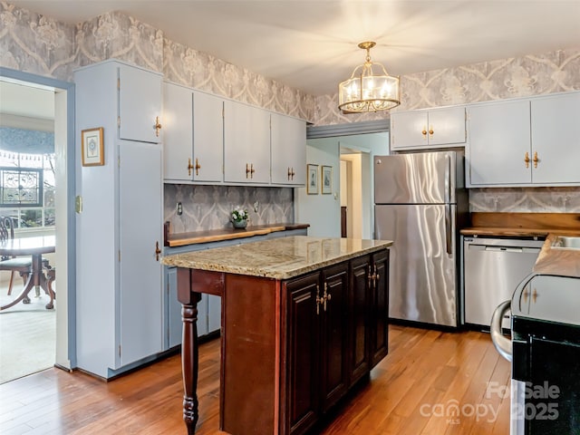 kitchen featuring stainless steel appliances, a kitchen bar, tasteful backsplash, a kitchen island, and pendant lighting