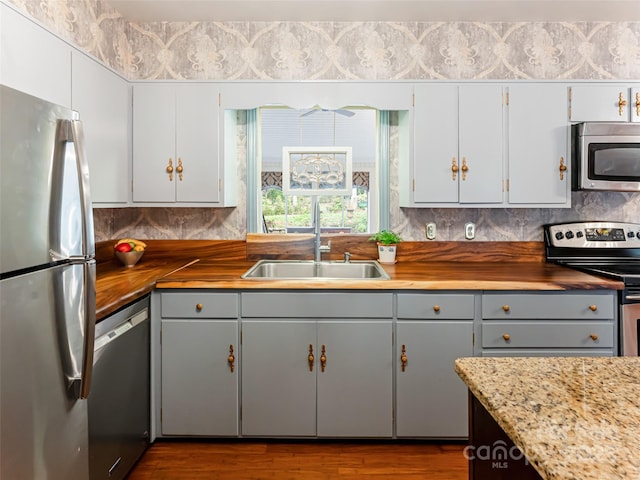 kitchen with white cabinets, gray cabinets, stainless steel appliances, sink, and butcher block counters