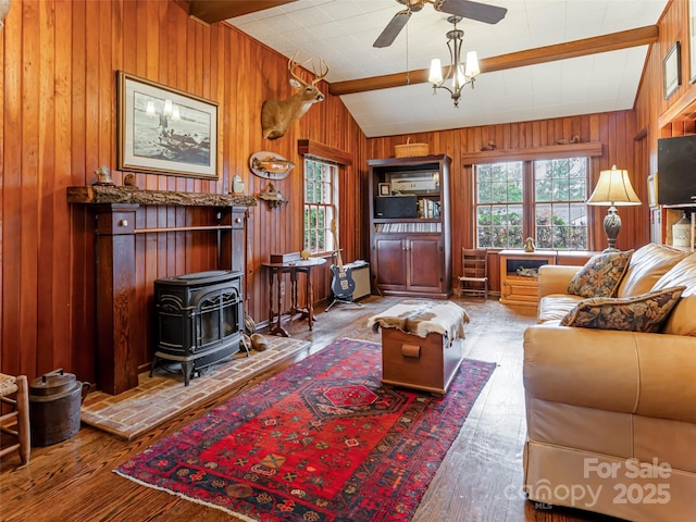 living room with hardwood / wood-style floors, wooden walls, a wood stove, and vaulted ceiling with beams