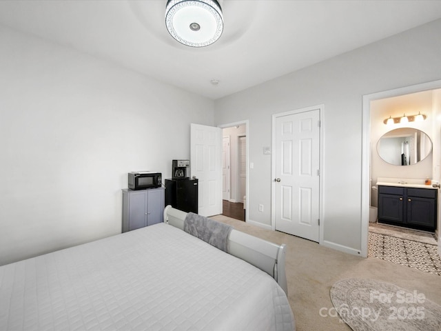 bedroom featuring ensuite bathroom and light colored carpet