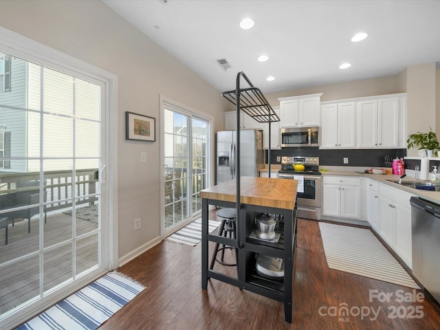 kitchen with butcher block counters, white cabinets, dark hardwood / wood-style floors, and stainless steel appliances