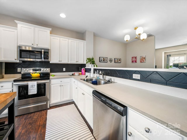 kitchen with stainless steel appliances, backsplash, white cabinetry, and sink